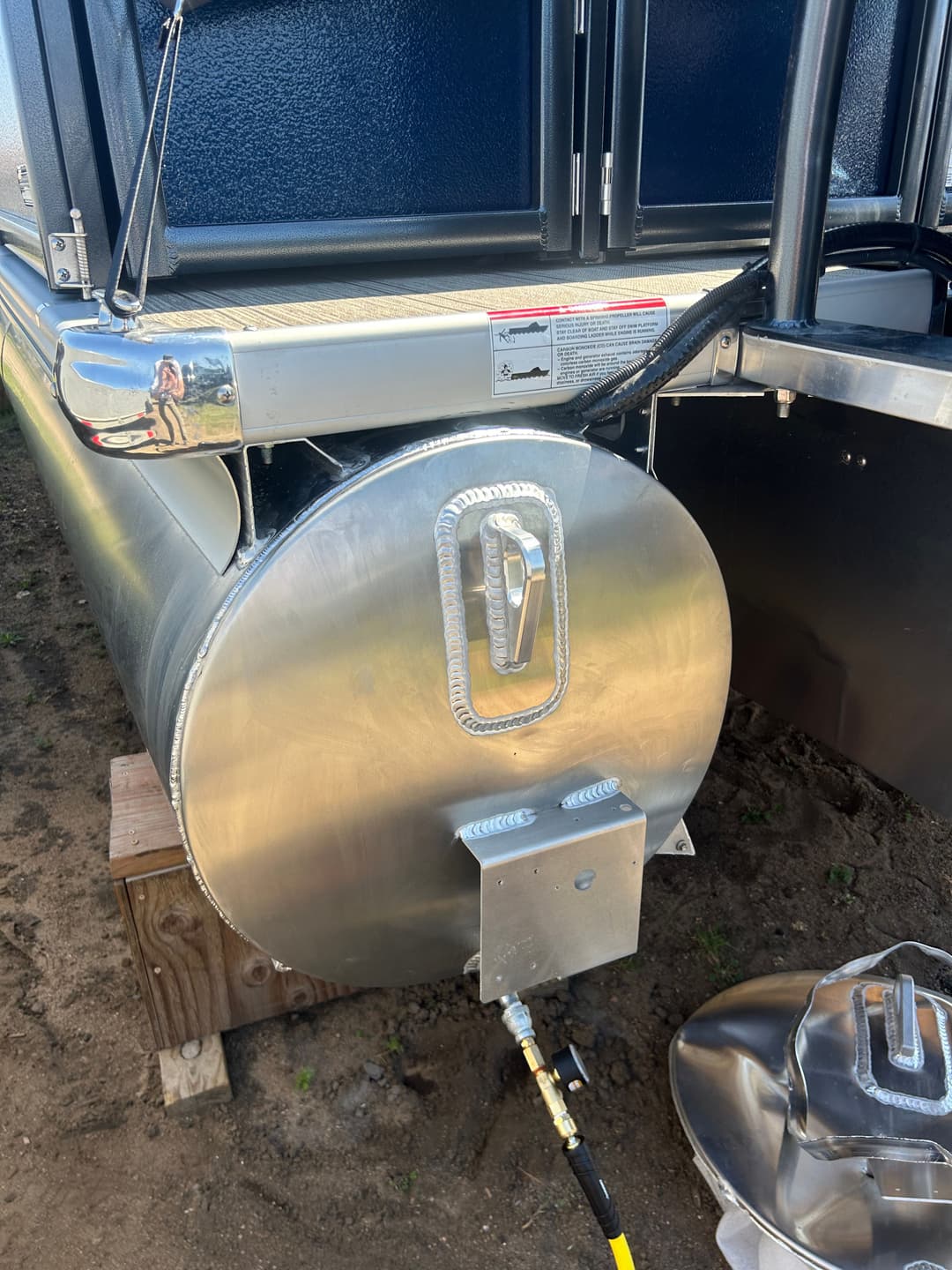 Stainless steel fuel tank with connecting hose on a trailer, showcasing clean design and functionality.