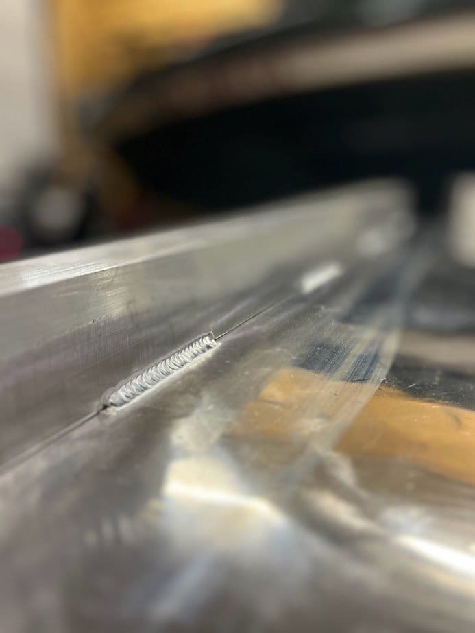 Close-up of a metal welding seam on aluminum, showcasing precision and craftsmanship.