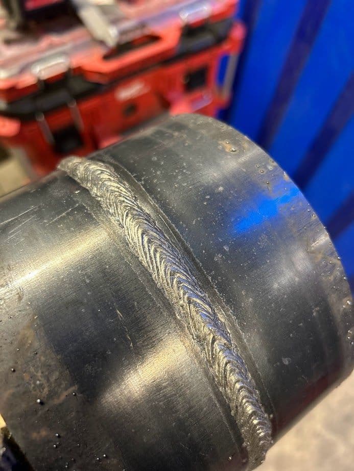 Close-up of a black pipe joint with a detailed metal weld, showcasing craftsmanship.