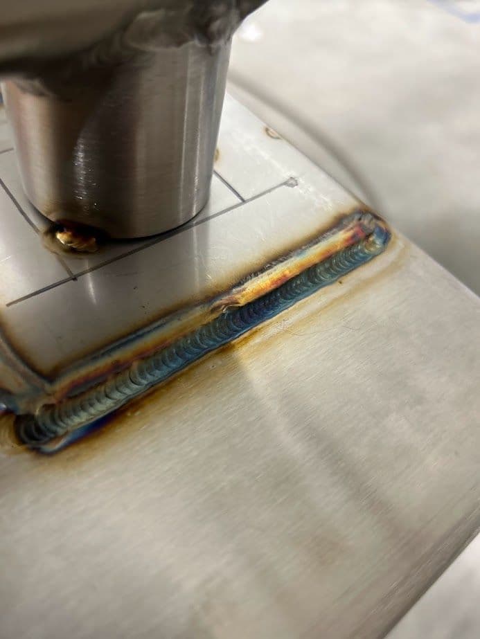 Close-up of a stainless steel weld joint showcasing vibrant colors and beading detail.