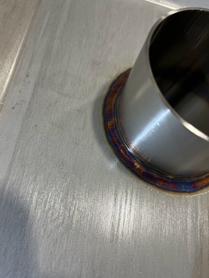 Metal pipe with colorful threaded seal on a shiny surface.