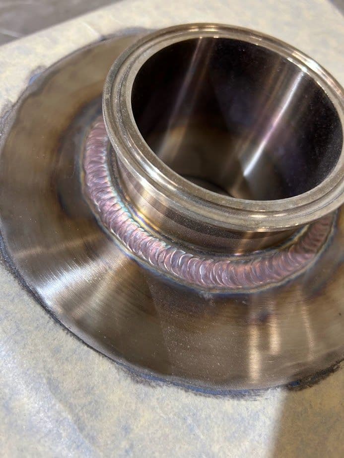 Close-up of a stainless steel pipe fitting with a detailed weld joint.