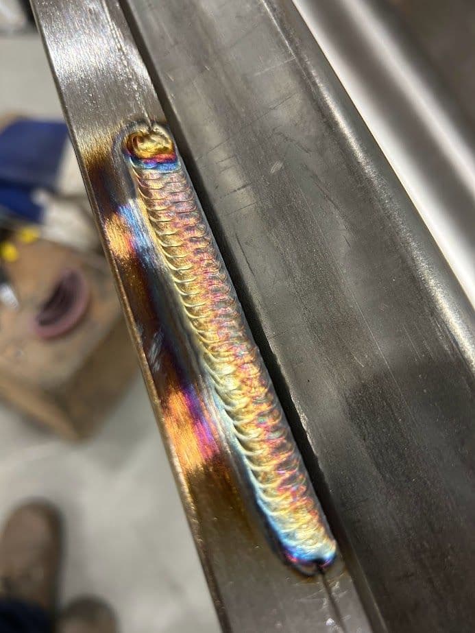 Close-up of a colorful welded seam on metal, showcasing detailed welding technique.