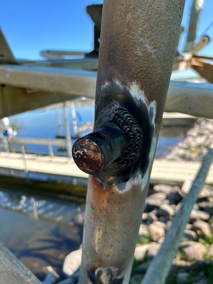 Welded metal component on a structure by the water, highlighting details and corrosion.