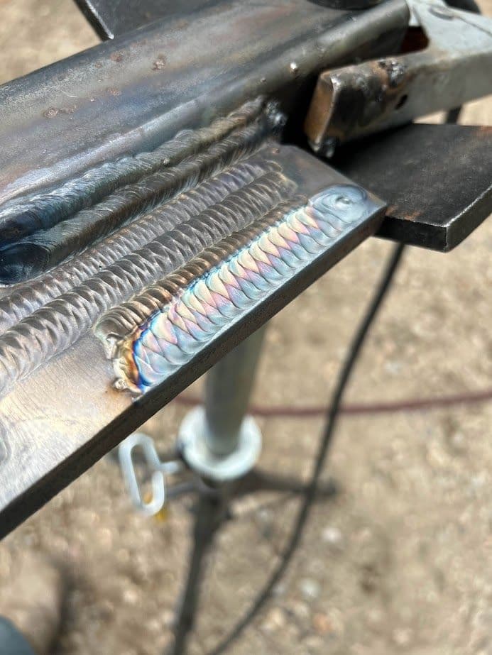 Close-up of metallic surface showcasing a detailed, colorful welded seam.