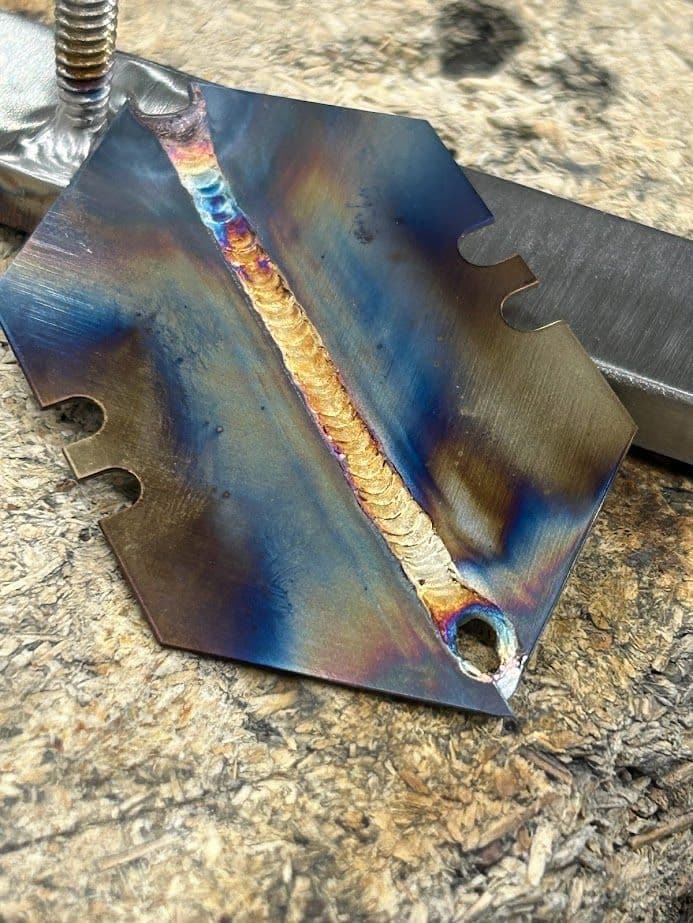 Detailed metal weld showcasing vibrant colors and patterns on a steel surface.