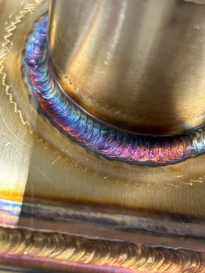 Close-up of a vibrant metal weld showing intricate bead patterns and color variations.