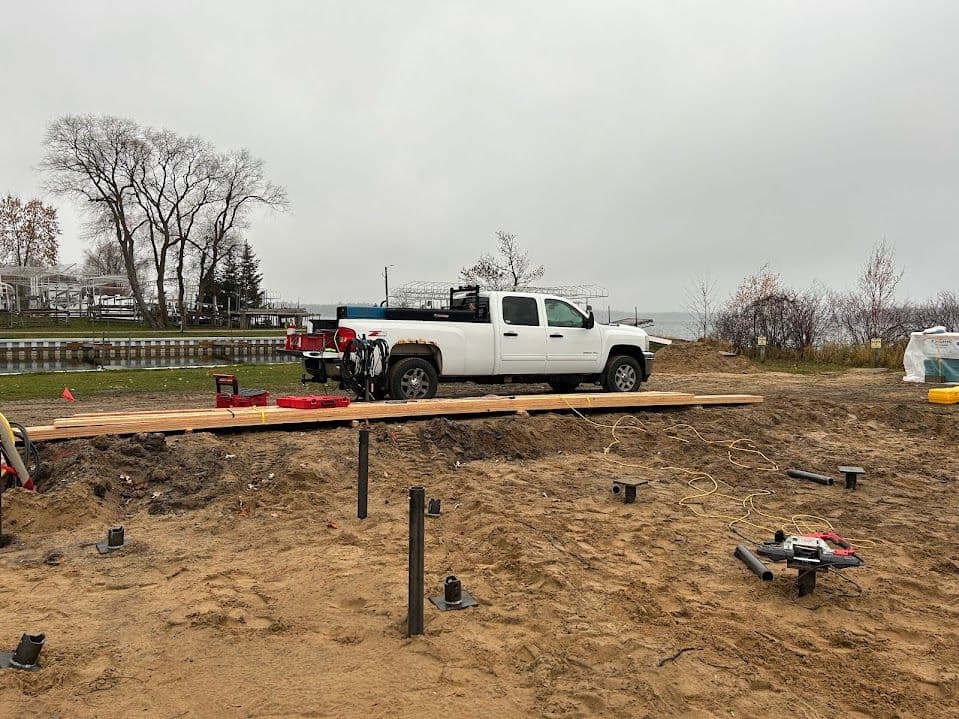 Construction truck on a sandy site with wooden planks and equipment for building project.