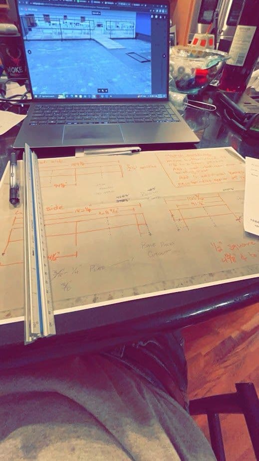 Blueprints and laptop on a table, showing design plans and measurements for a project.