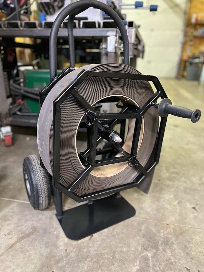 Heavy-duty wire spool cart with large reel, designed for easy transport in a workshop.
