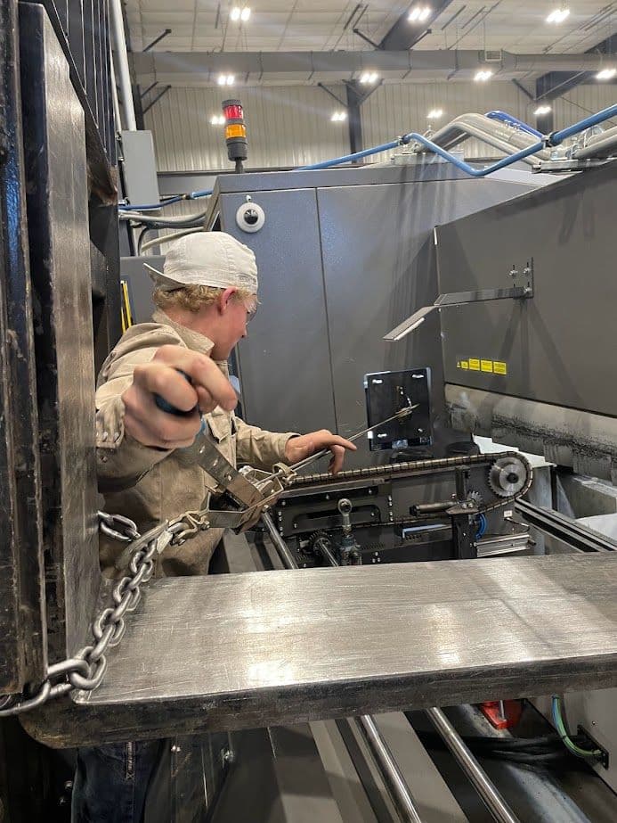 Worker operating machinery in manufacturing facility, focusing on equipment maintenance.