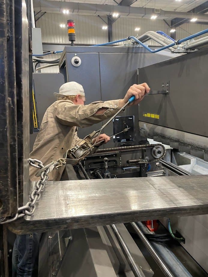 Worker operating machinery in a manufacturing facility, focusing on precision equipment settings.
