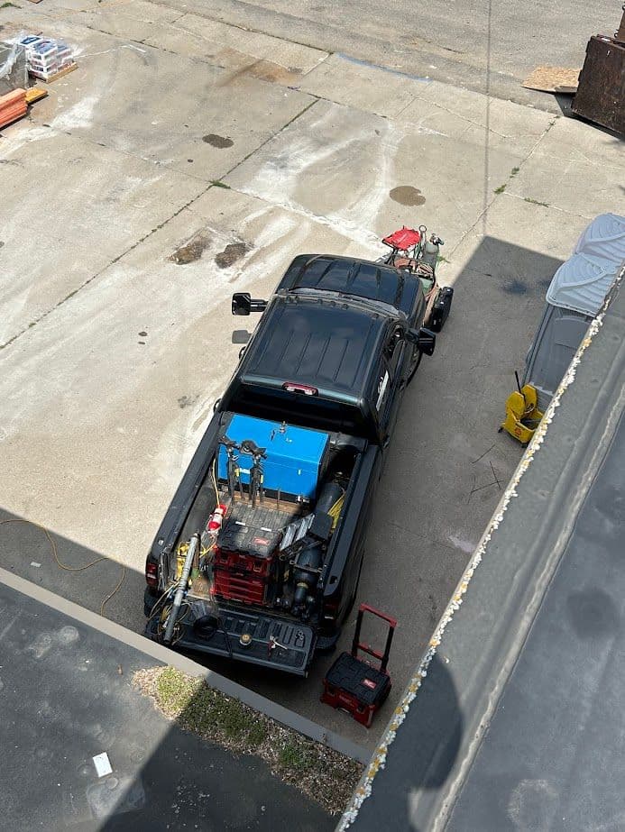 Black pickup truck parked on a concrete surface with tools and equipment in the bed.