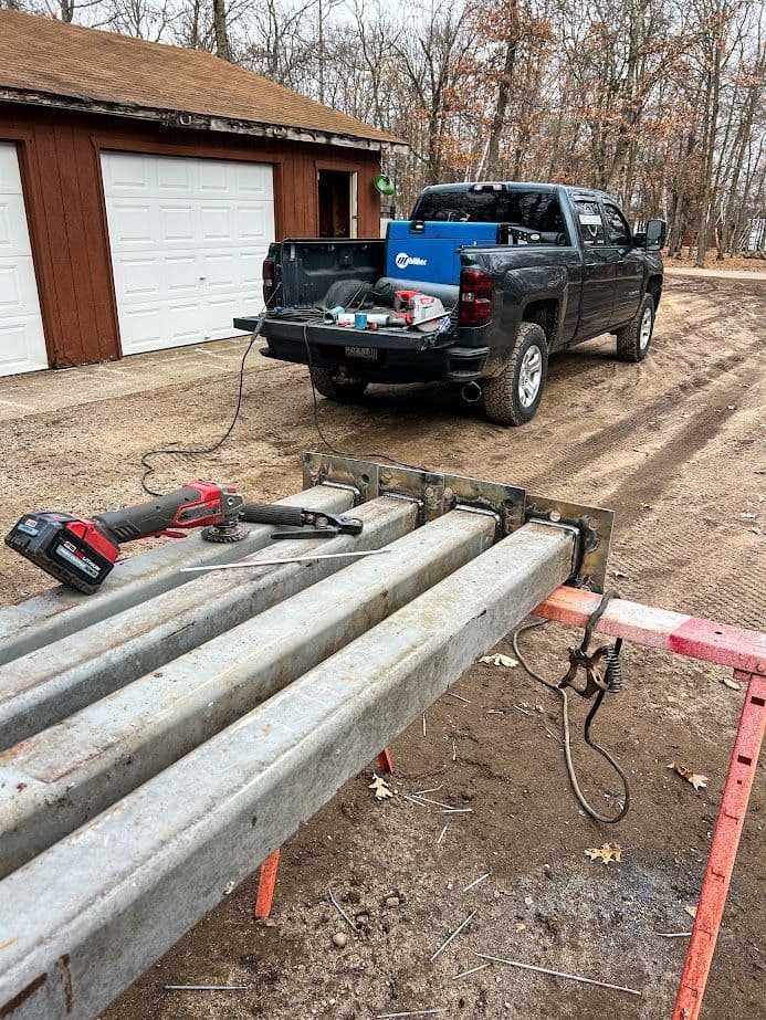 Worksite setup with metal beams, power tools, and a black pickup truck in a gravel area.