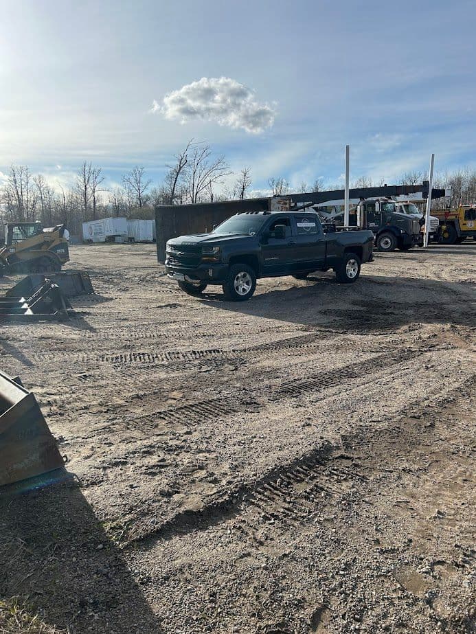 Heavy-duty pickup truck parked on a gravel lot with construction equipment in the background.