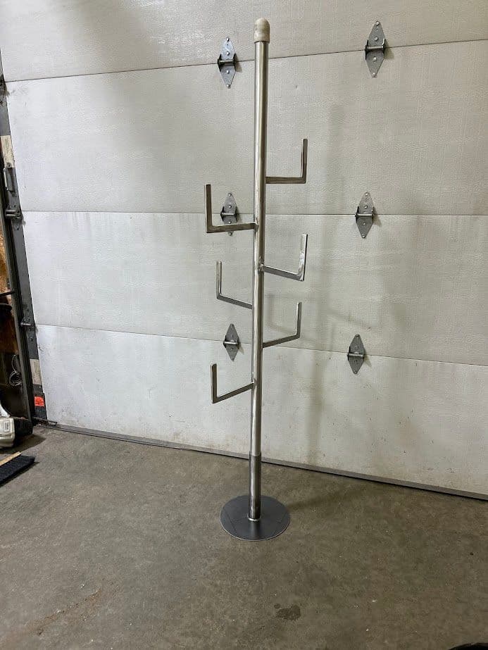 Metal coat rack with multiple arms and a sturdy base, set against a garage door background.