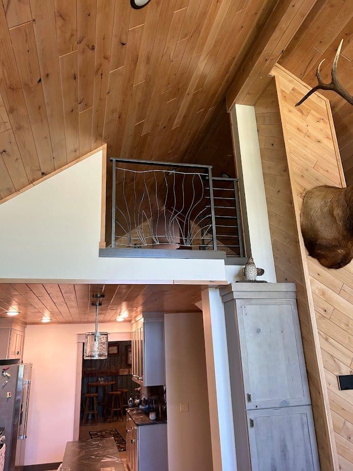 Modern cabin interior with wooden ceilings, open loft, and stylish railing features.