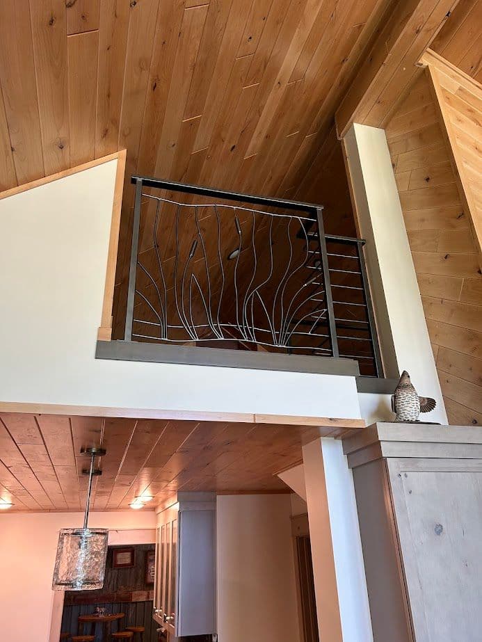 Stylish wooden interior with a decorative iron railing and chandelier lighting.