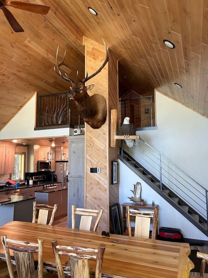 Rustic dining area featuring a mounted moose head, wooden accents, and modern kitchen design.