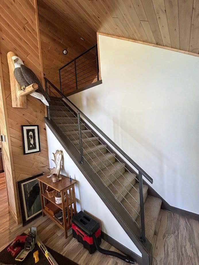 Staircase with wooden walls, metal railing, and decorative eagle mount in cozy interior.