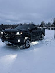 Black Chevrolet truck on snowy landscape, showcasing winter driving capabilities.