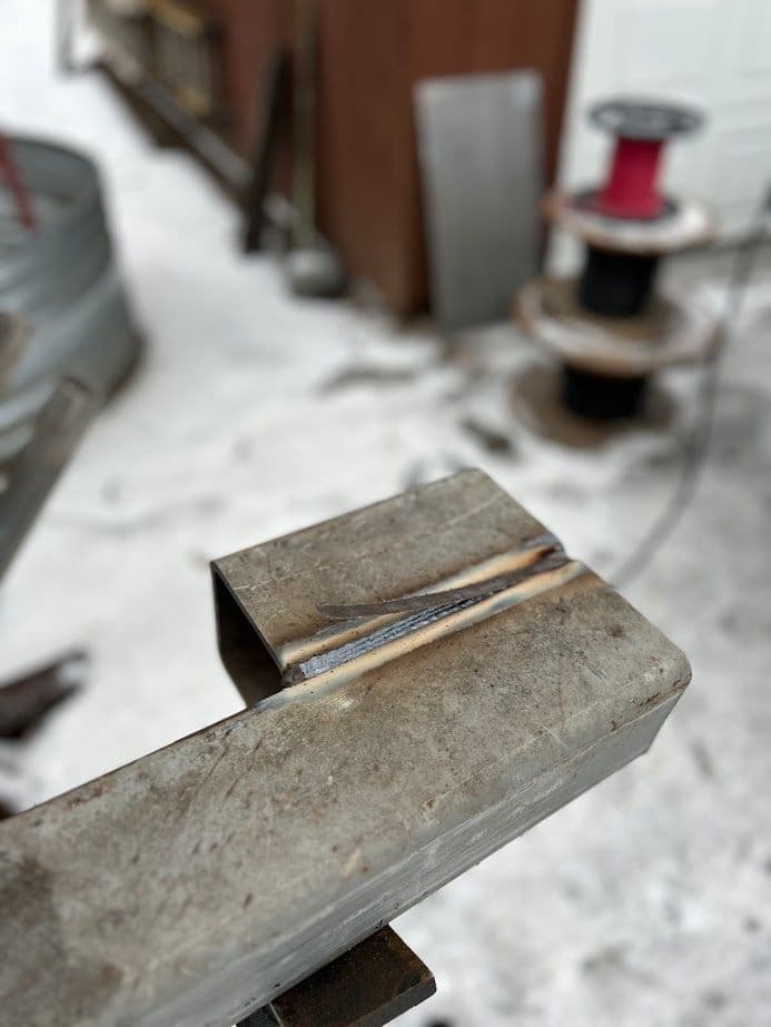 Close-up of steel metalwork with visible weld seam in a workshop setting.