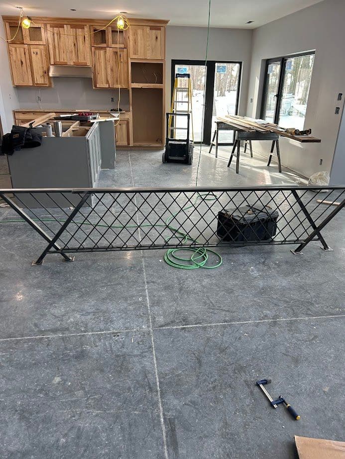 Interior construction progress showing wooden cabinets, a metal railing, and unfinished flooring.