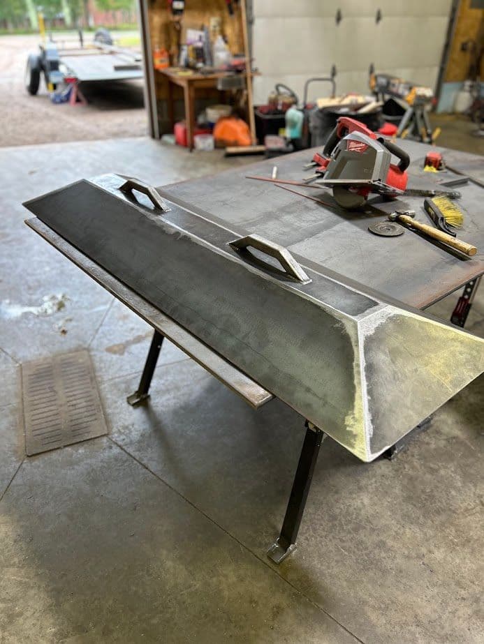 Metal fabrication project featuring a large, unfinished steel piece on a workshop table.