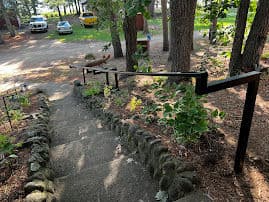 Stairway with metal railing surrounded by trees and green plants in a serene outdoor setting.