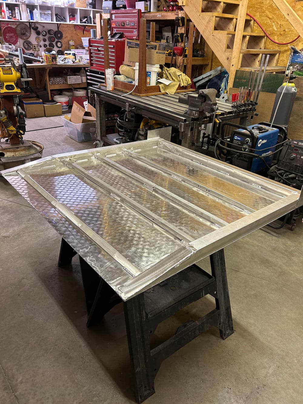 Aluminum fabrication on a worktable in a workshop with tools and materials in the background.