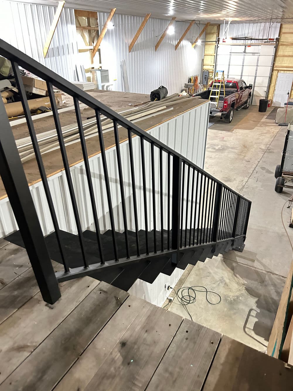 Black metal railing staircase leading down in a spacious industrial garage.