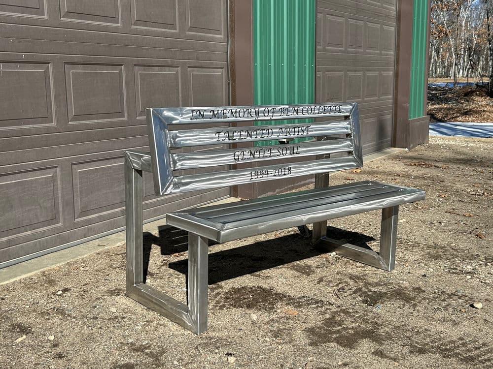 Metal memorial bench dedicated to Gene C. Smith, honoring his memory with engraved text.